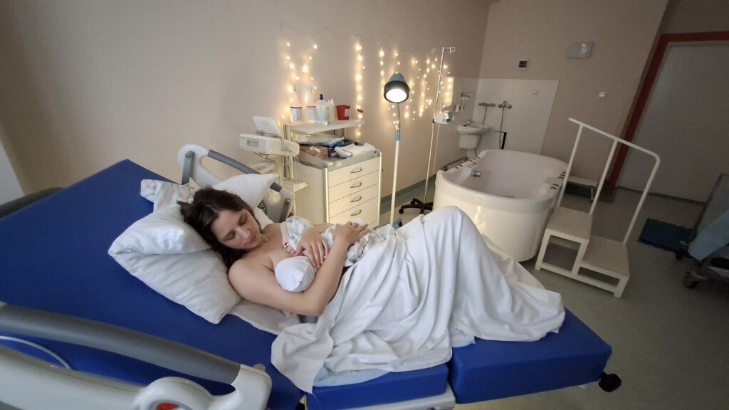 Sala porodowa. Kobieta z noworodkiem po porodzie.